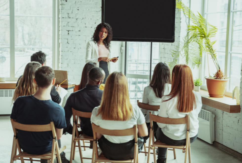 a person giving a presentation in a remote work space to a small group of seated people
