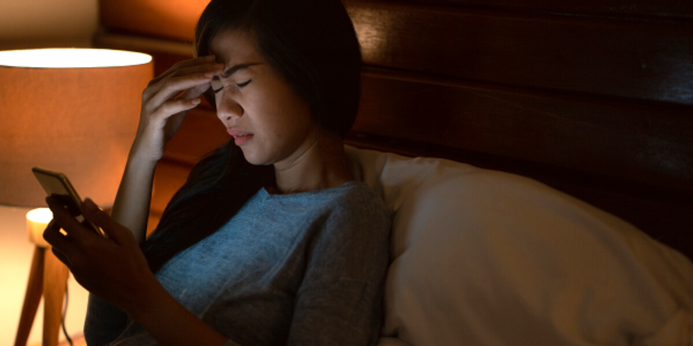 Woman in bed receiving a text about work from a coworker after hours